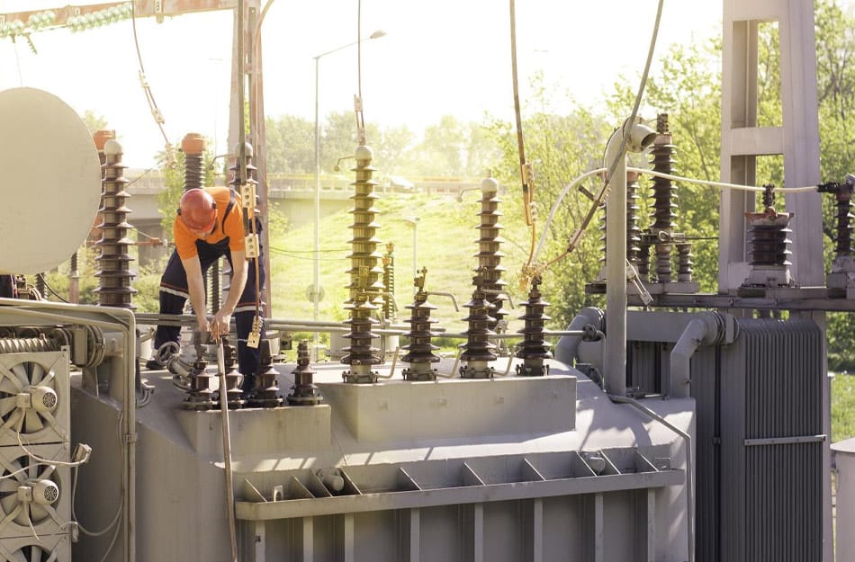 Technician inspecting an industrial power transformer
