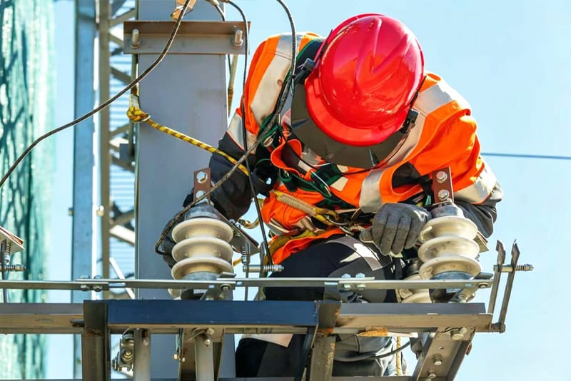 Electrical technician inspecting power line connections and insulators